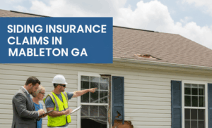 A man in a suit, a woman, and a contractor in a hard hat and safety vest are inspecting significant damage to the siding and a broken window of a house. The contractor is pointing towards the damage while holding a clipboard. A blue tarp with some siding pieces is on the grass.