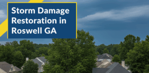 An aerial view shows a roofer in a yellow safety vest and hard hat on a residential roof in Roswell, GA, inspecting damage near fallen tree branches after a storm. The neighborhood is surrounded by green trees under a dramatic, cloudy sky. The image features a badge blue and canary yellow overlay with the title "Storm Damage Restoration in Roswell GA" in white text.